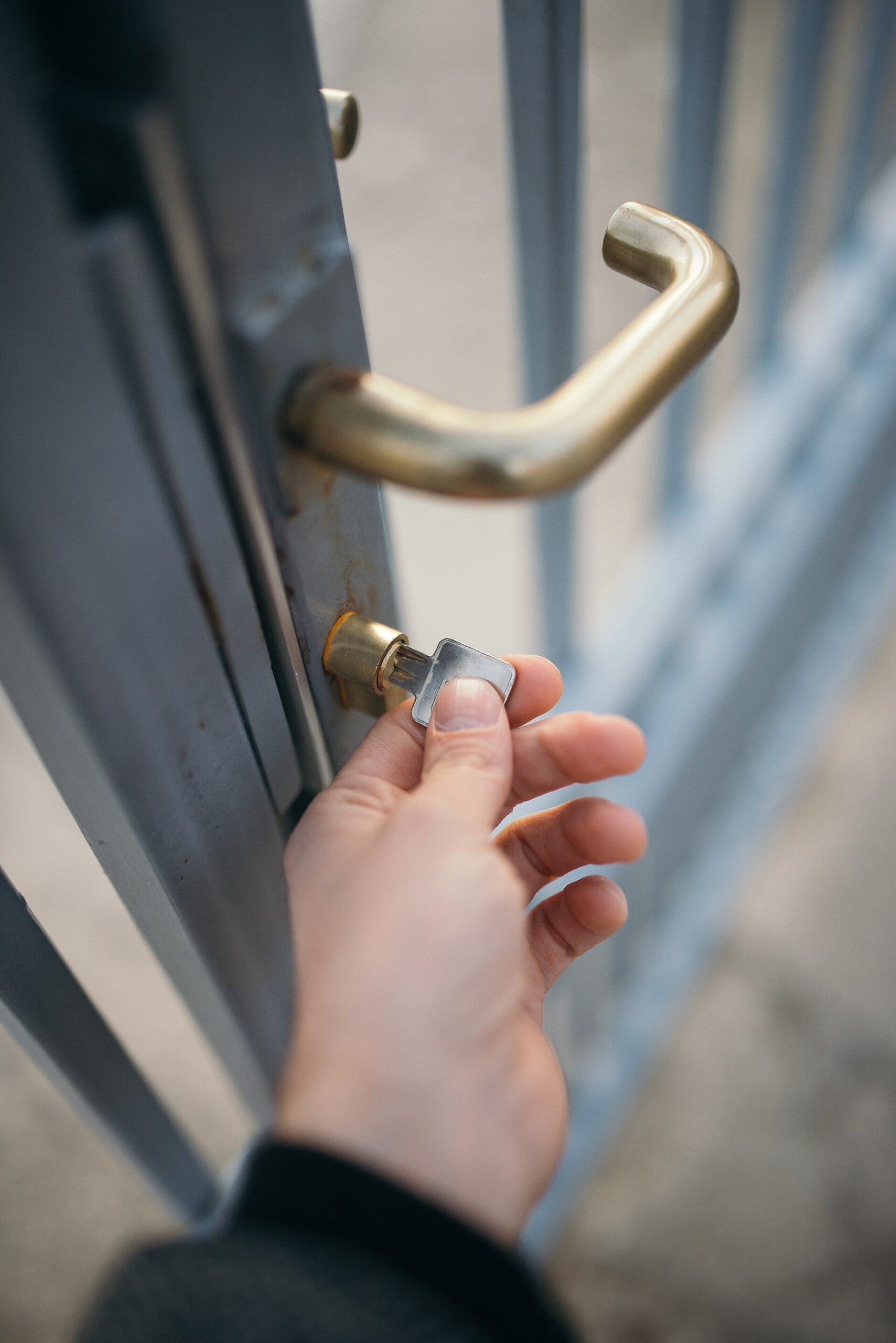 Main insérant une clé dans la serrure d'un portail métallique